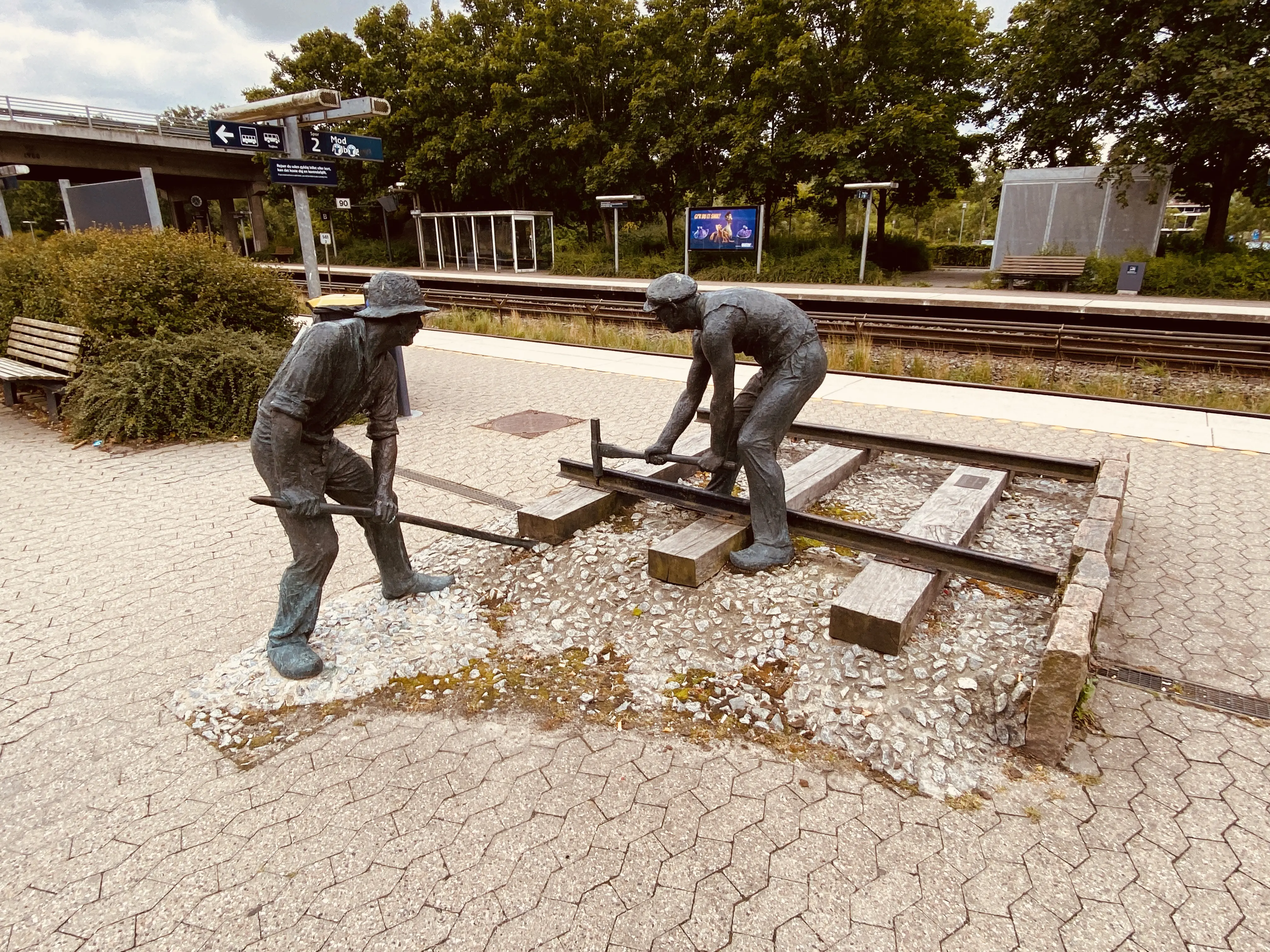 Billede af skulpturen af jernbanebørsterne ved den nye Hadsten Stations stationsbygning i Hadsten.