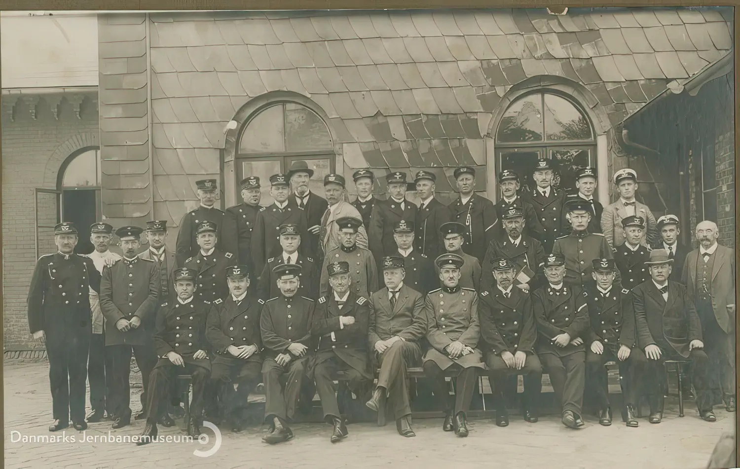 Tysk og det dansk jernbanepersonale opstillet til fælles gruppefotografering ved Stationsvej foran stationsbygningen efter den danske overtagelse af stationen natten mellem den 16. og 17. jun. 1920.