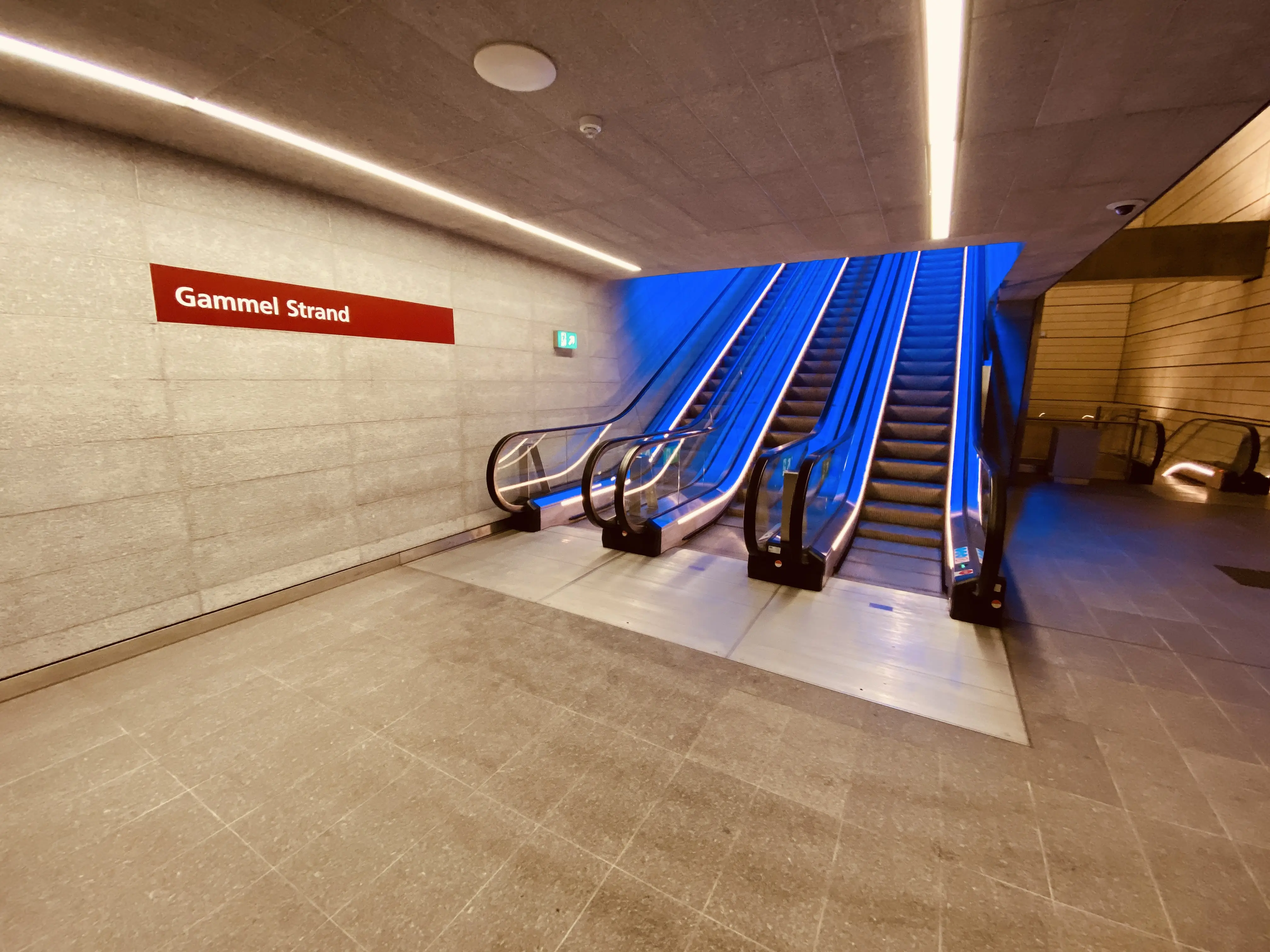 Billede af Gammel Strand Metrostation med et blåt lysspil, som er en hilsen til sollyset i vandoverfladen i Gammel Strands kanal, der løber lige ved siden af stationen.