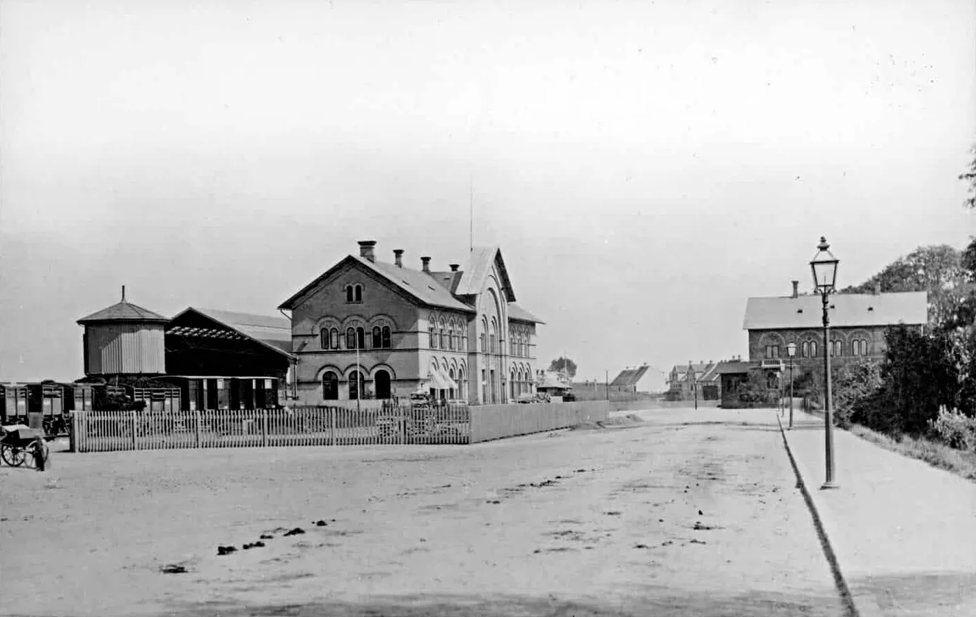 Billede af Odense Banegård - de lave bygninger i baggrunden er huse i Dannebrogsgade. Bygningen til højre er det nye banegårdsposthus, som blev revet ned i 1895.