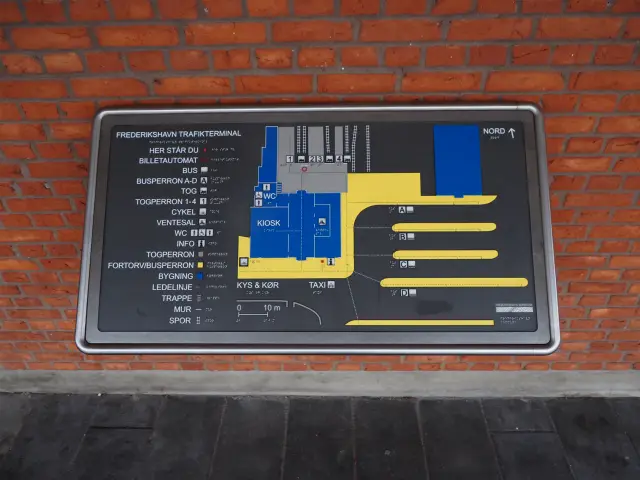 Billede af Frederikshavn Station set fra vejsiden. Informasjon og orienteringsplakat
