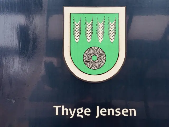 Billede af Aulums byvåben og navngivet "Thyge Jensen - Æ' Rejsepost" på siden af DSB MF 5082 fotograferet ud for København Hovedbanegård.